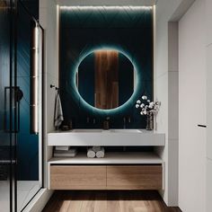 a modern bathroom with wood flooring and blue wallpaper on the walls, along with an oval mirror