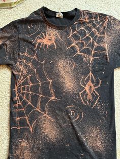 a black t - shirt with spider webs on it