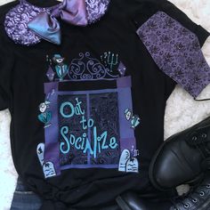 a black shirt with purple and blue designs on the front is next to some boots