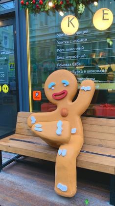 a large ginger sitting on top of a wooden bench in front of a store window