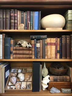 a book shelf filled with lots of books next to a white vase and other items