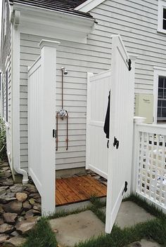 an outdoor shower in front of a white house