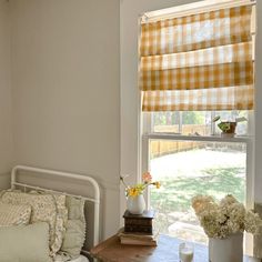 a bed sitting under a window next to a table with flowers on top of it