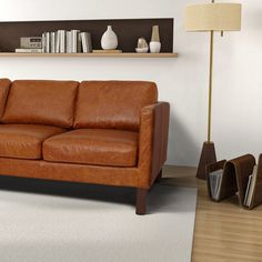 a brown leather couch sitting on top of a wooden floor next to a book shelf