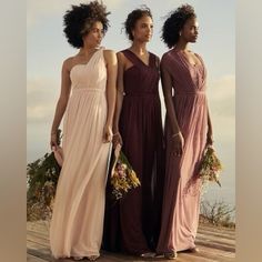 three women in long dresses standing on a wooden platform