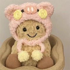 a teddy bear wearing a pink hat and scarf sitting in a dog bed with its paws on the ground