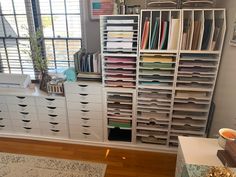 a room filled with lots of drawers next to a wall mounted bookcase and window