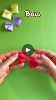 two hands are holding origami bows on a green background