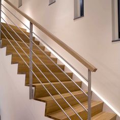 a wooden stair case next to a white wall