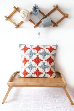 a pillow sitting on top of a wooden bench next to a crochet hook