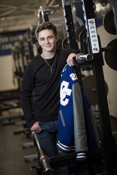 a man standing in front of a gym machine holding onto a jersey with the number 33 on it