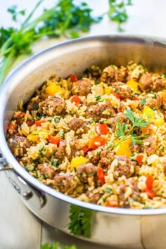 a large pot filled with rice and meat on top of a table next to parsley