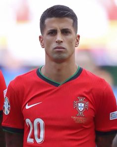 a soccer player is standing with his head turned to the side and looking at the camera