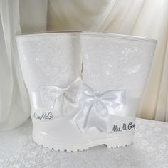 a pair of white boots with bows and name tags on the side, sitting on a table