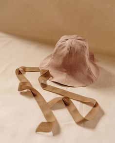 a hat is laying on the bed next to it's strap, which has been tied down