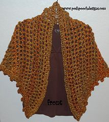 an orange crocheted shawl hanging on a wall next to a brown t - shirt