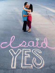 a man and woman standing in the middle of an empty parking lot with words written on it