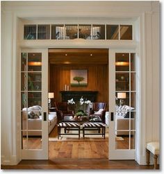 an open door leading to a living room with wood floors and white trim on the walls