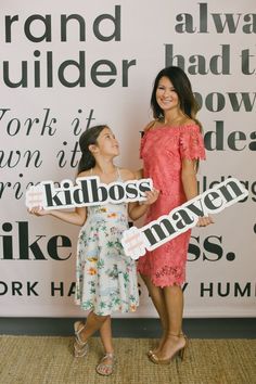 two women standing next to each other holding signs