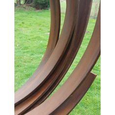 three metal sculptures sitting on top of a lush green field