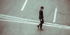 a man walking across a street next to a cross walk