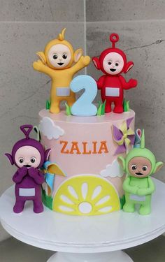 a three tiered cake decorated with cartoon figures and the number two on it's side