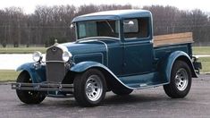 an old blue truck parked in a parking lot