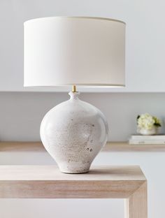 a white lamp sitting on top of a wooden table