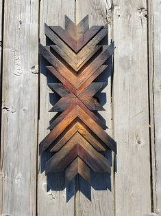 a wooden wall hanging on the side of a building with an arrow made out of wood