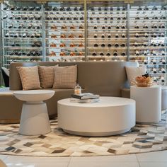 a living room filled with furniture and lots of wine bottles on the wall behind it