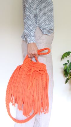 a woman is holding an orange handbag