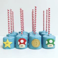 four nintendo themed candles are lined up with candy canes and mario's hat