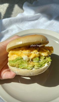 a person is holding a sandwich with eggs and guacamole on the bun