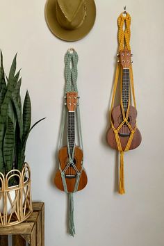 three wall hangings with hats on them and plants in the corner next to them