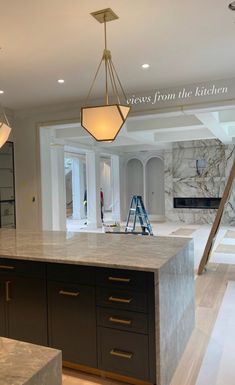 a kitchen with marble counter tops and an island in the foreground is being remodeled