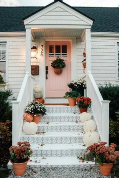 front porch decorated for fall with pumpkins and flowers on the steps to the door