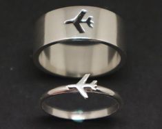 two silver rings with an airplane symbol on the side and one in the middle, against a black background