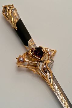 a fancy gold and black knife with pearls on it's blade is laying on a white surface