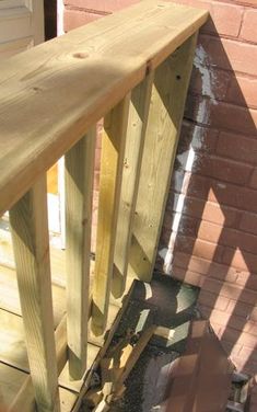 a wooden hand rail next to a brick wall