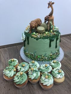 there is a cake and cupcakes on the table with green frosted icing