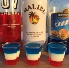 three shot glasses filled with blue and red drinks