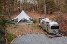 an rv parked next to a tent in the woods