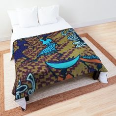 a bed with a colorful comforter on top of it next to a wooden floor