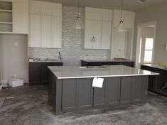 an empty kitchen with white cabinets and gray counter tops in the process of remodeling