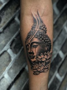 a black and white buddha tattoo on the arm