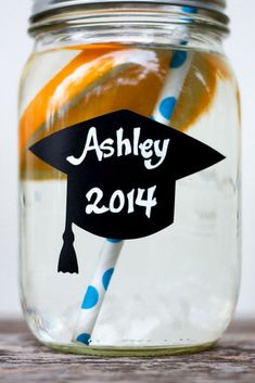 a mason jar filled with orange slices and graduation cap on top of a wooden table