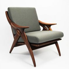 a chair that is sitting up against a white wall with a wooden frame and armrests