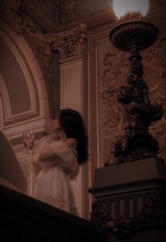 a woman in a white dress is standing on the stairs and looking down at something