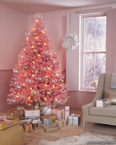 a pink christmas tree in the corner of a living room with presents on the floor