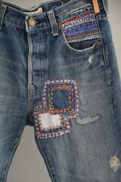 an old pair of jeans with colorful patches on the back and sides, are displayed